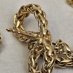 Close up of the textured braided gold-tone chain forming the bow