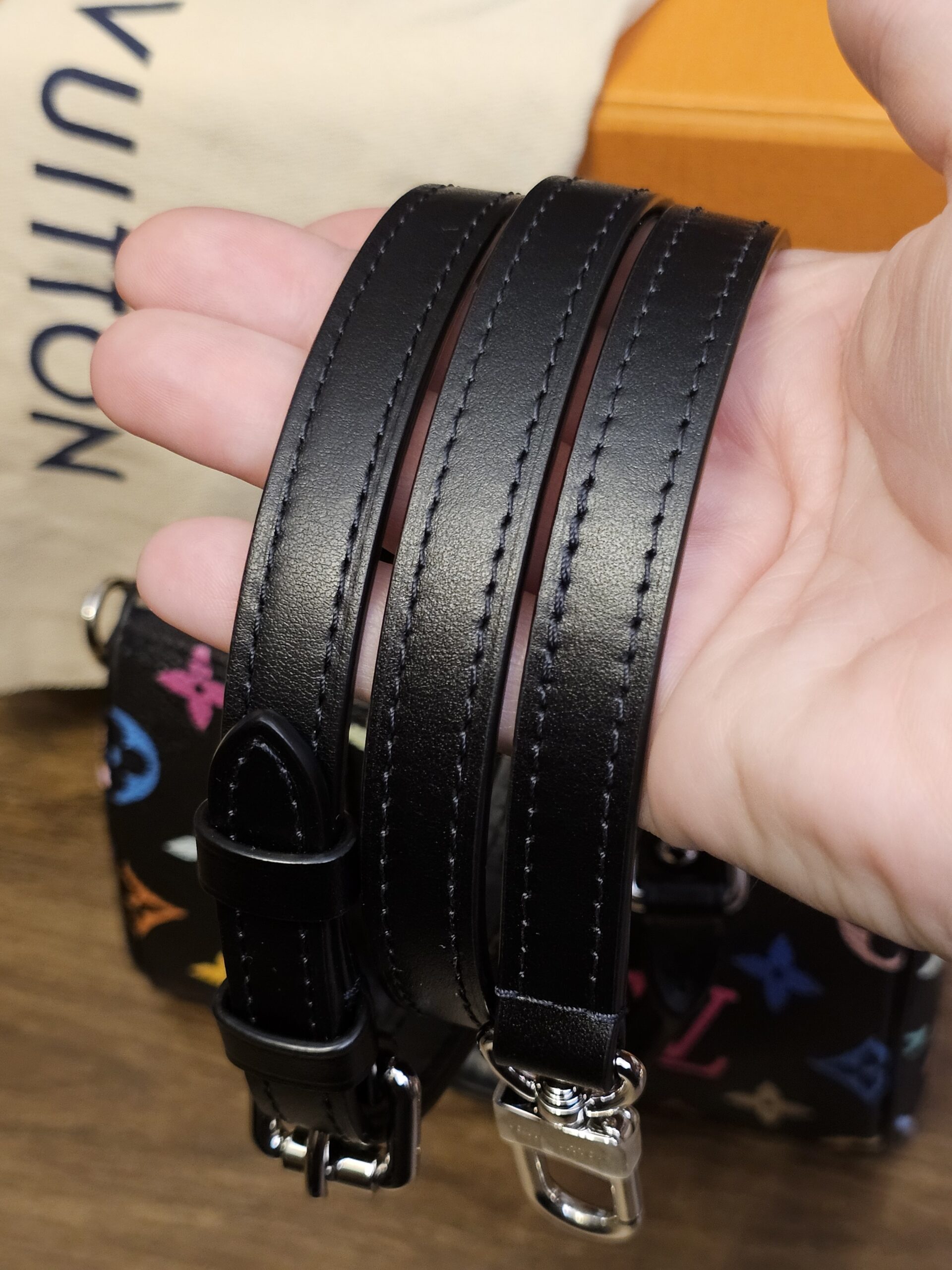 Removable black leather shoulder strap held in hand