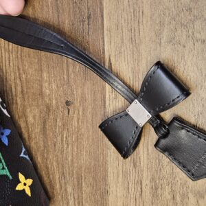 Black leather name tag and clochette laid on a wood surface
