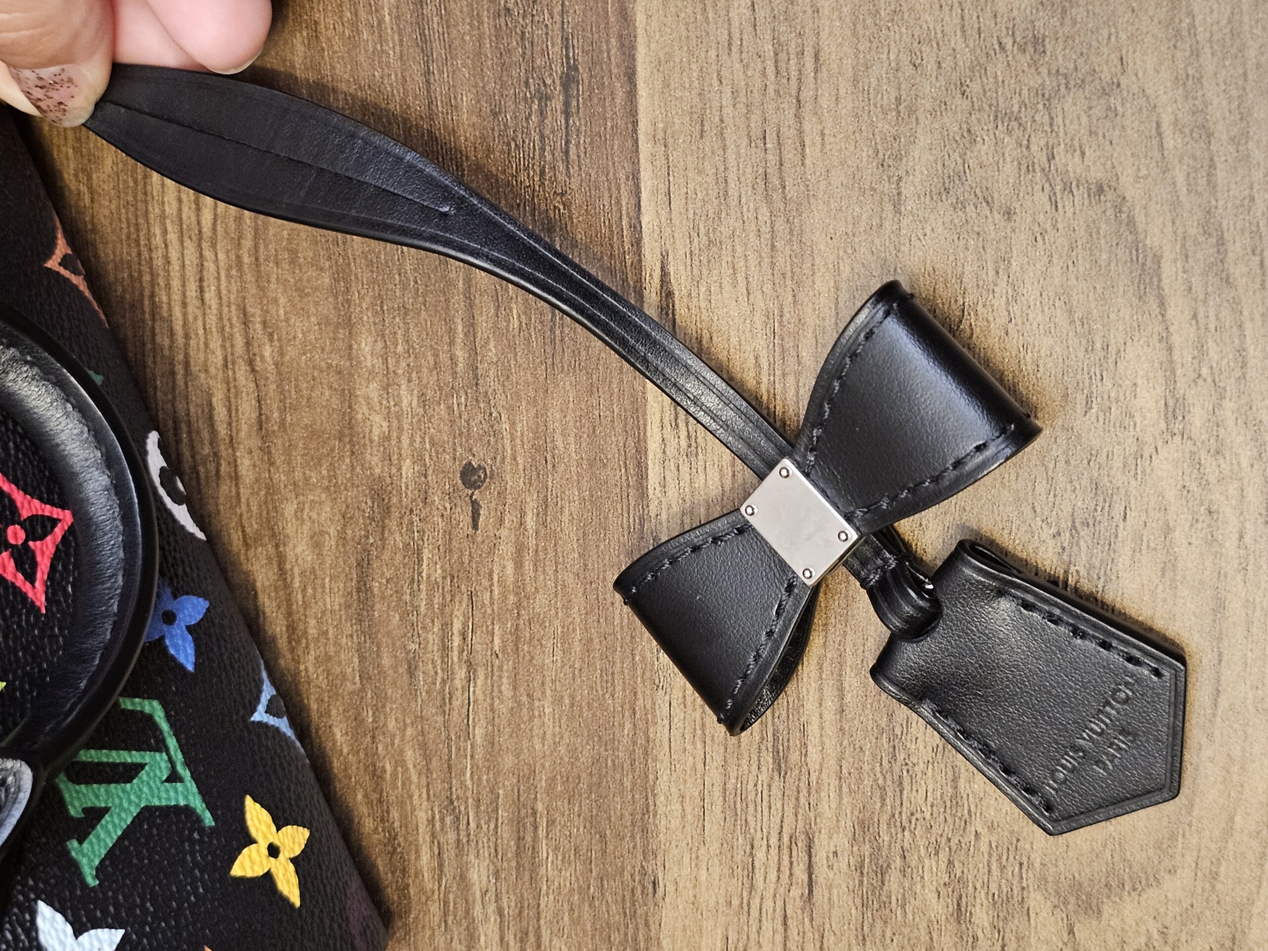Black leather name tag and clochette laid on a wood surface