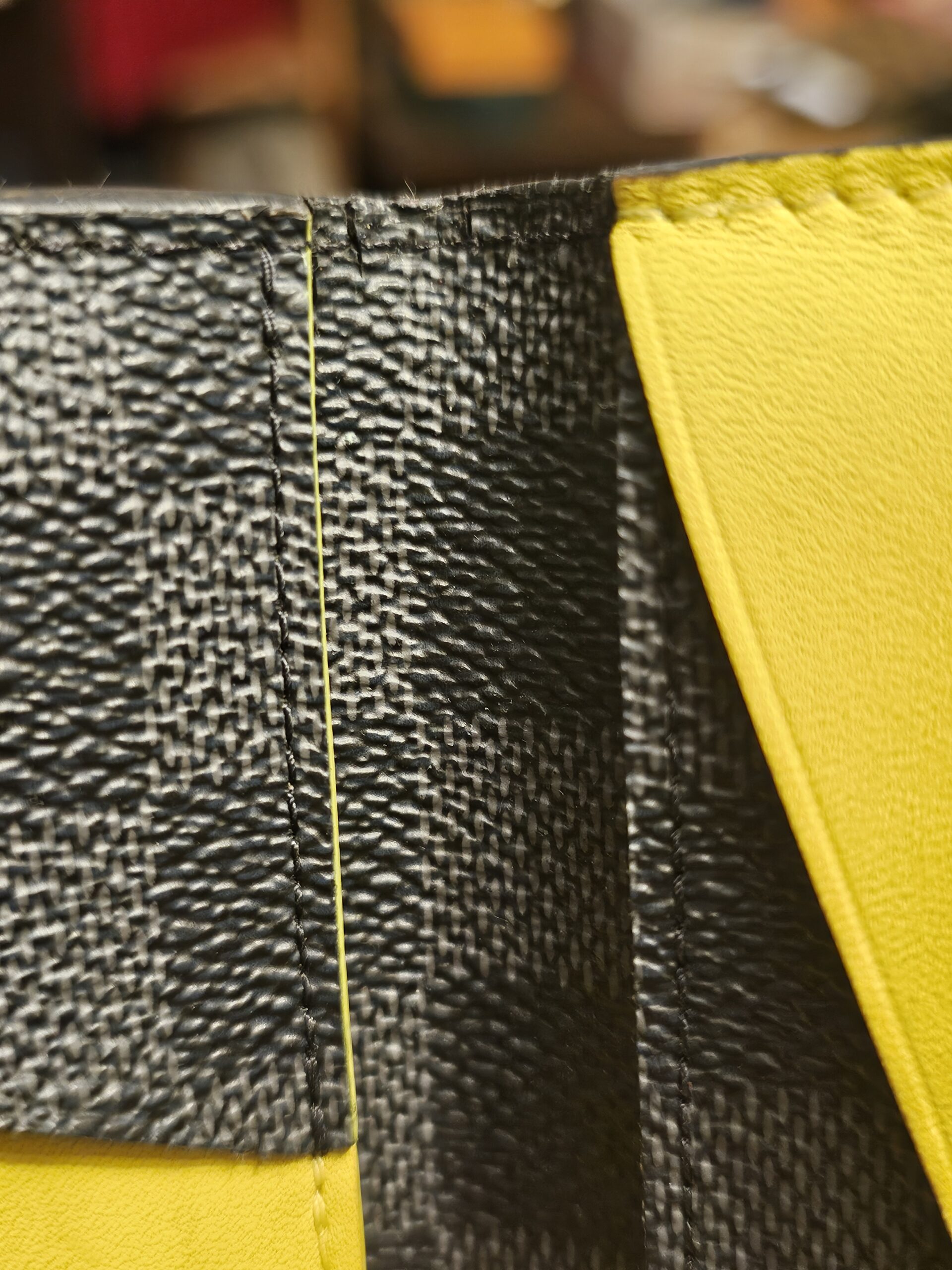 Close up of wear and cracking along the edge of the Damier Graphite canvas
