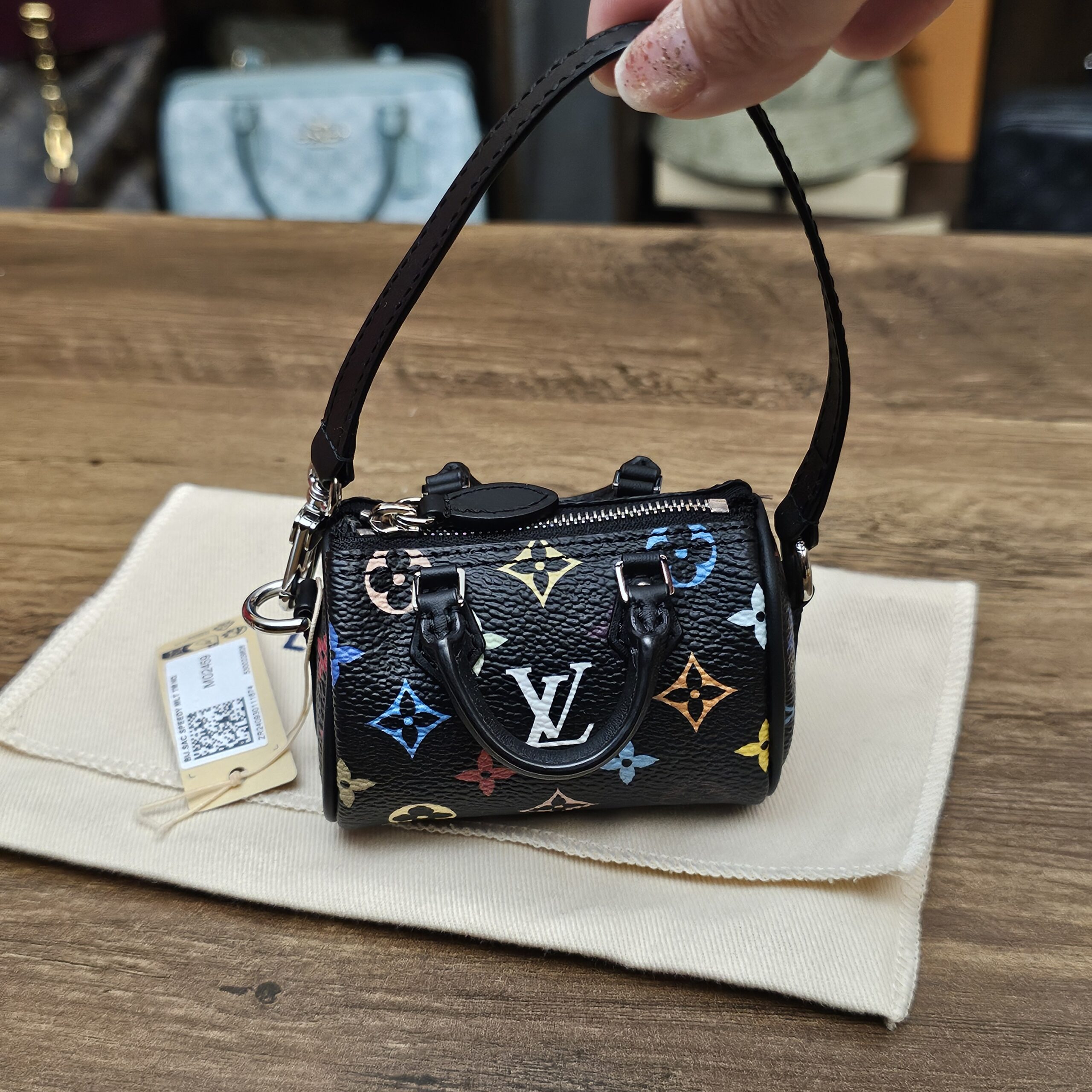 Louis Vuitton x Takashi Murakami Monogram Multicolor Micro Speedy Black - held by the strap with its retail tag
