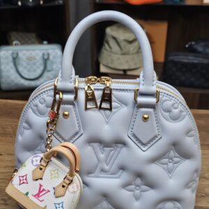 Charm hanging from a light blue quilted bag for scale