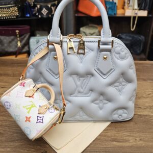 Micro Speedy hanging from a light blue quilted bag for scale