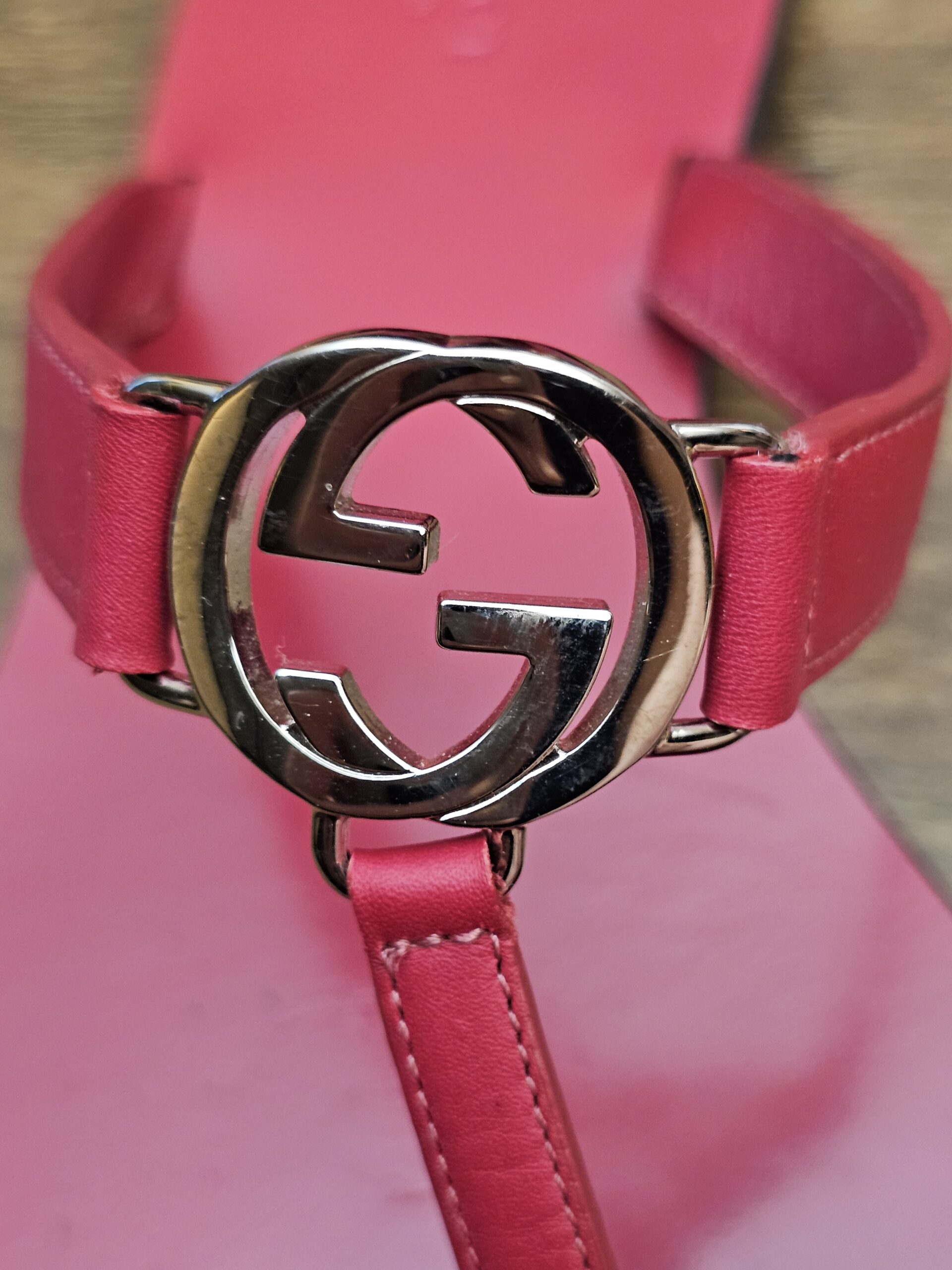 Close up of the silver-tone G logo buckle on the berry strap