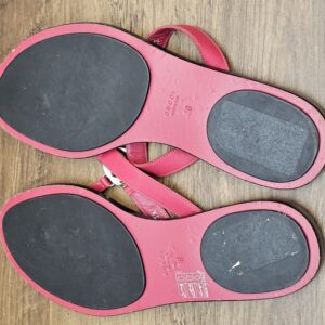 Soles of both sandals showing wear on the black pads
