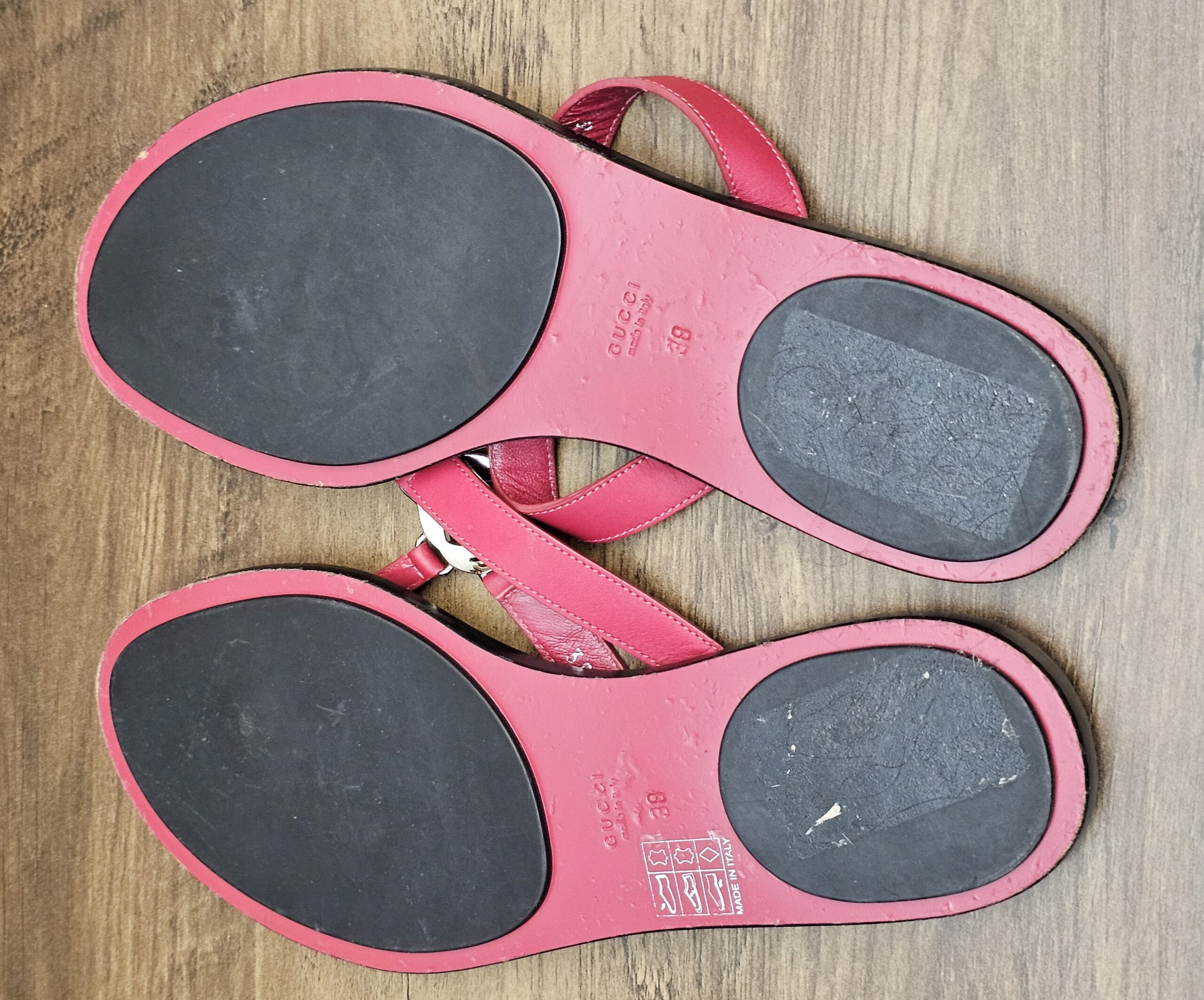 Soles of both sandals showing wear on the black pads