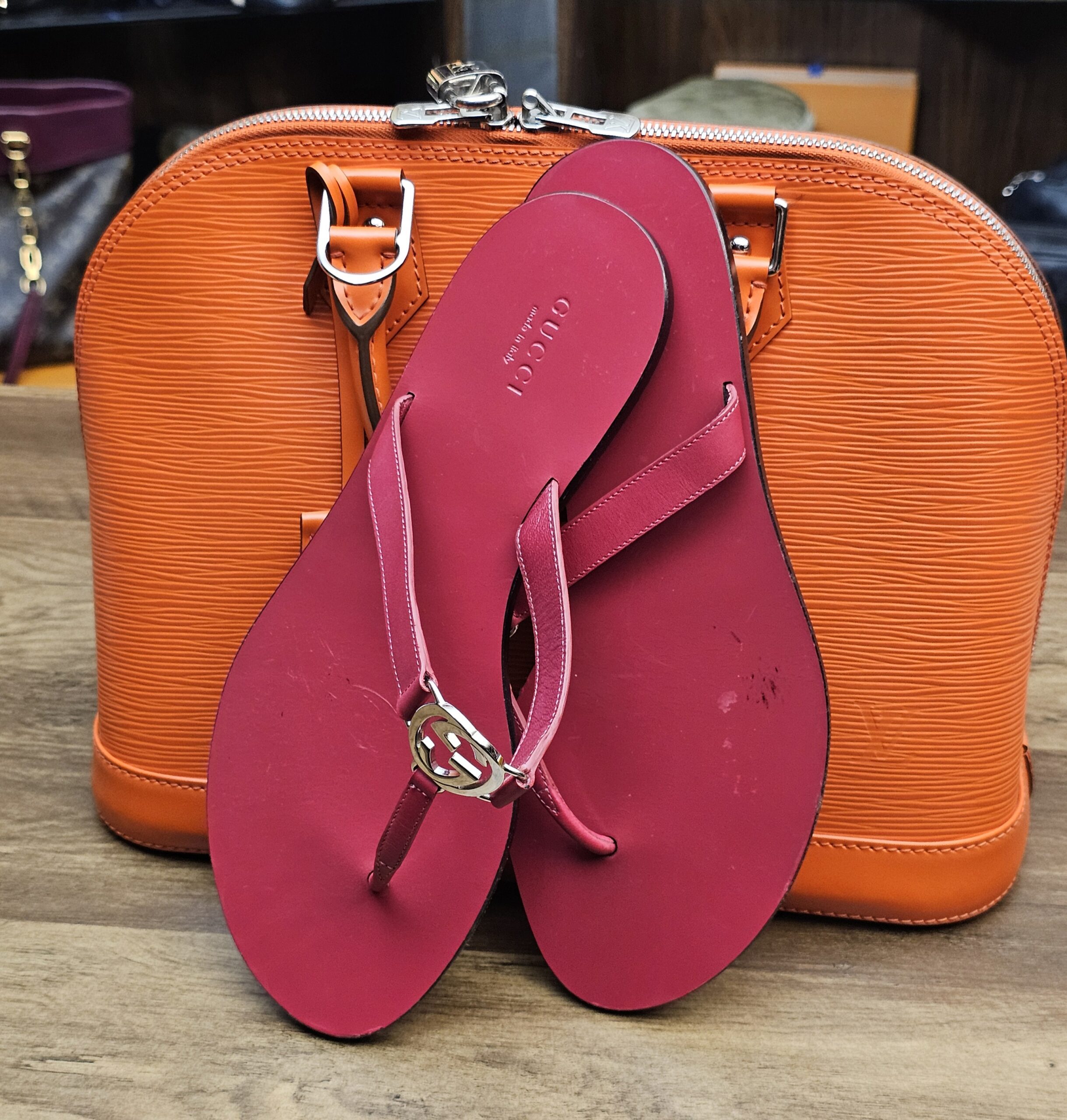 Sandal propped against an orange bag to show the berry color