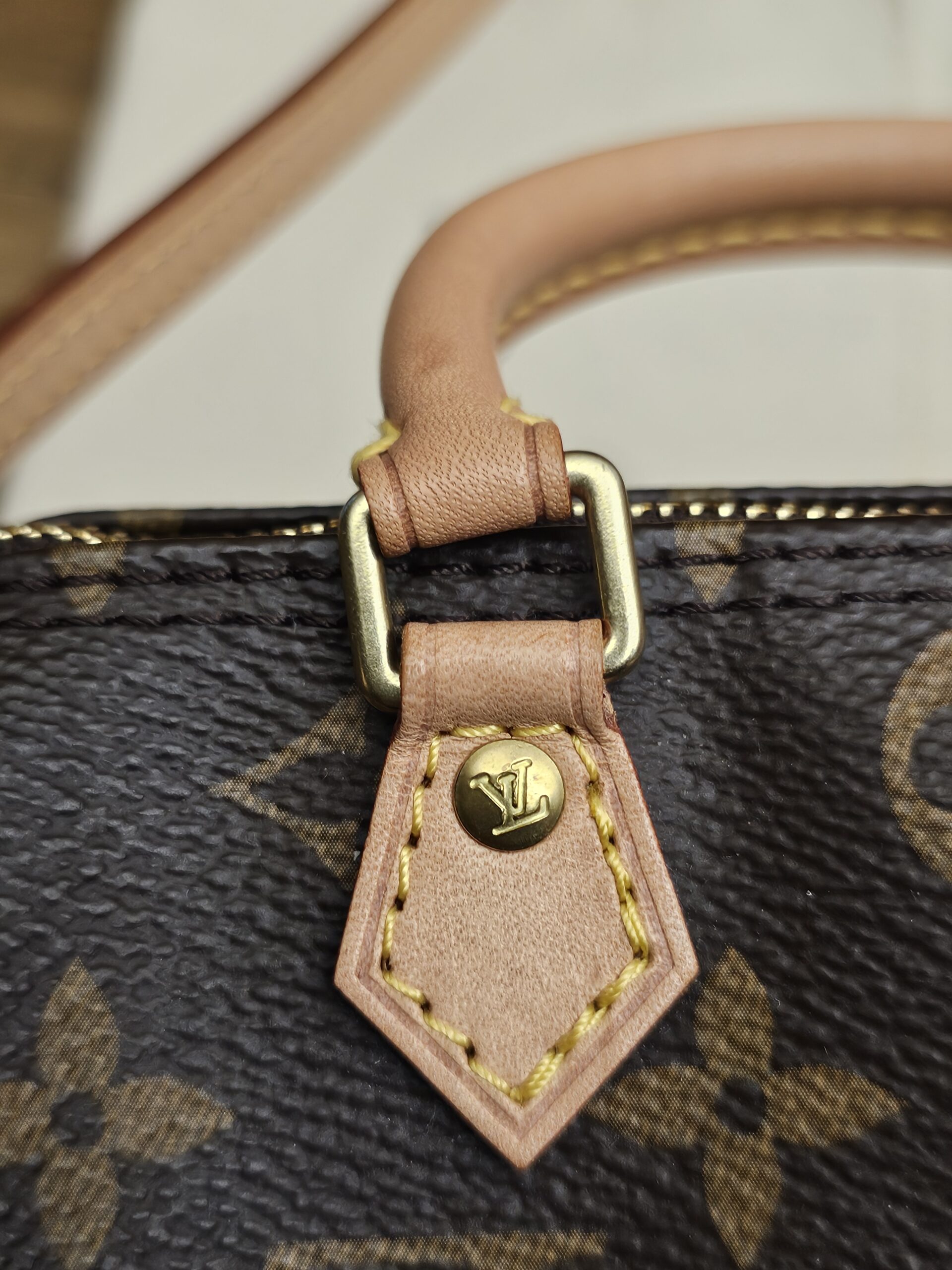 Close up of a vachetta tab and gold-tone handle ring
