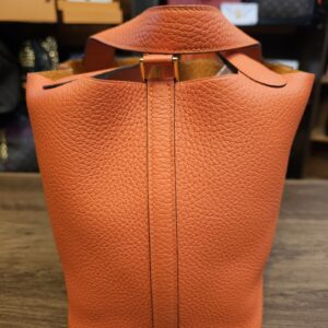 Side view showing the leather closure strap and gold-tone hardware