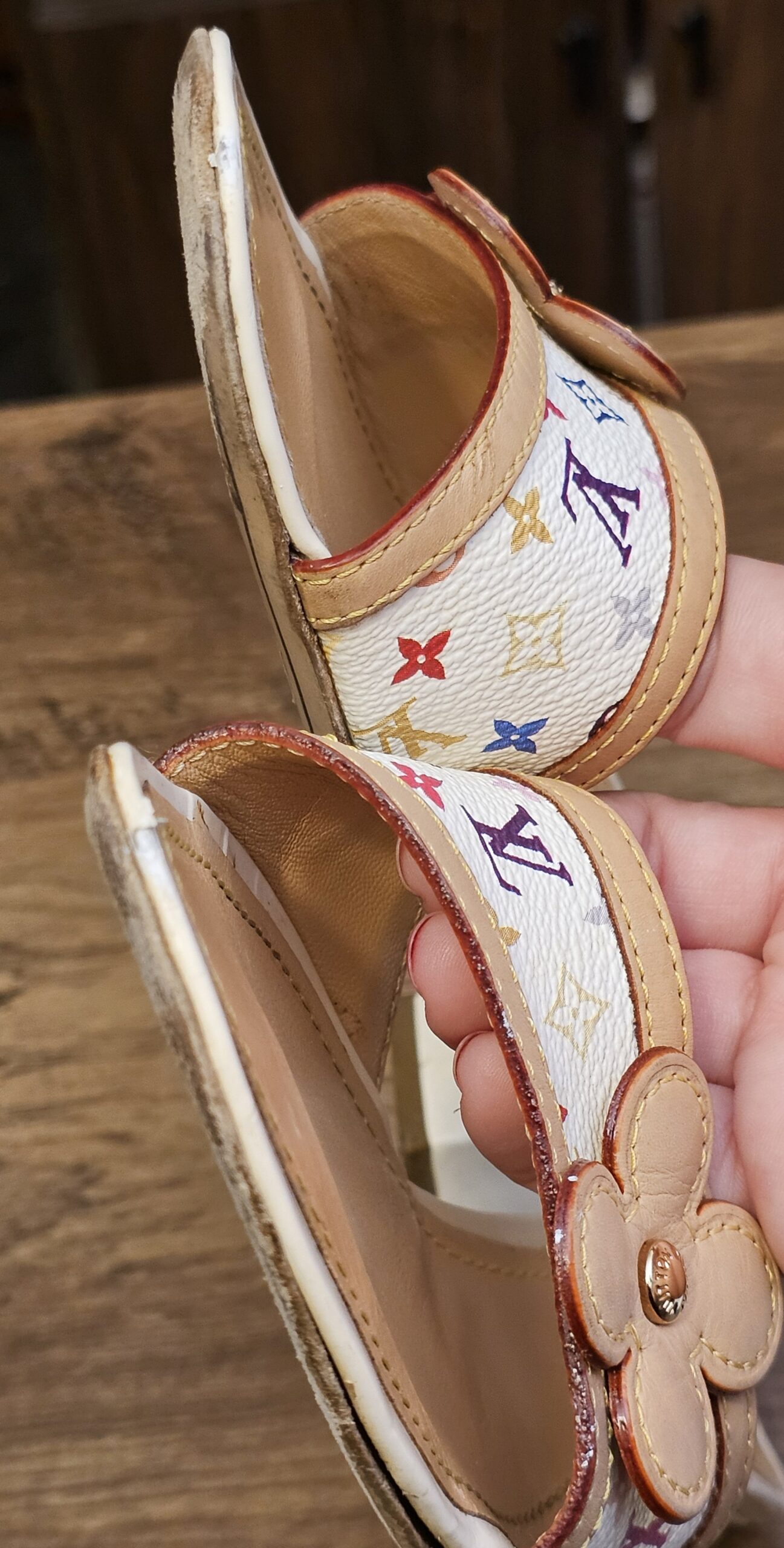 Mule held at an angle showing the strap edge and flower applique
