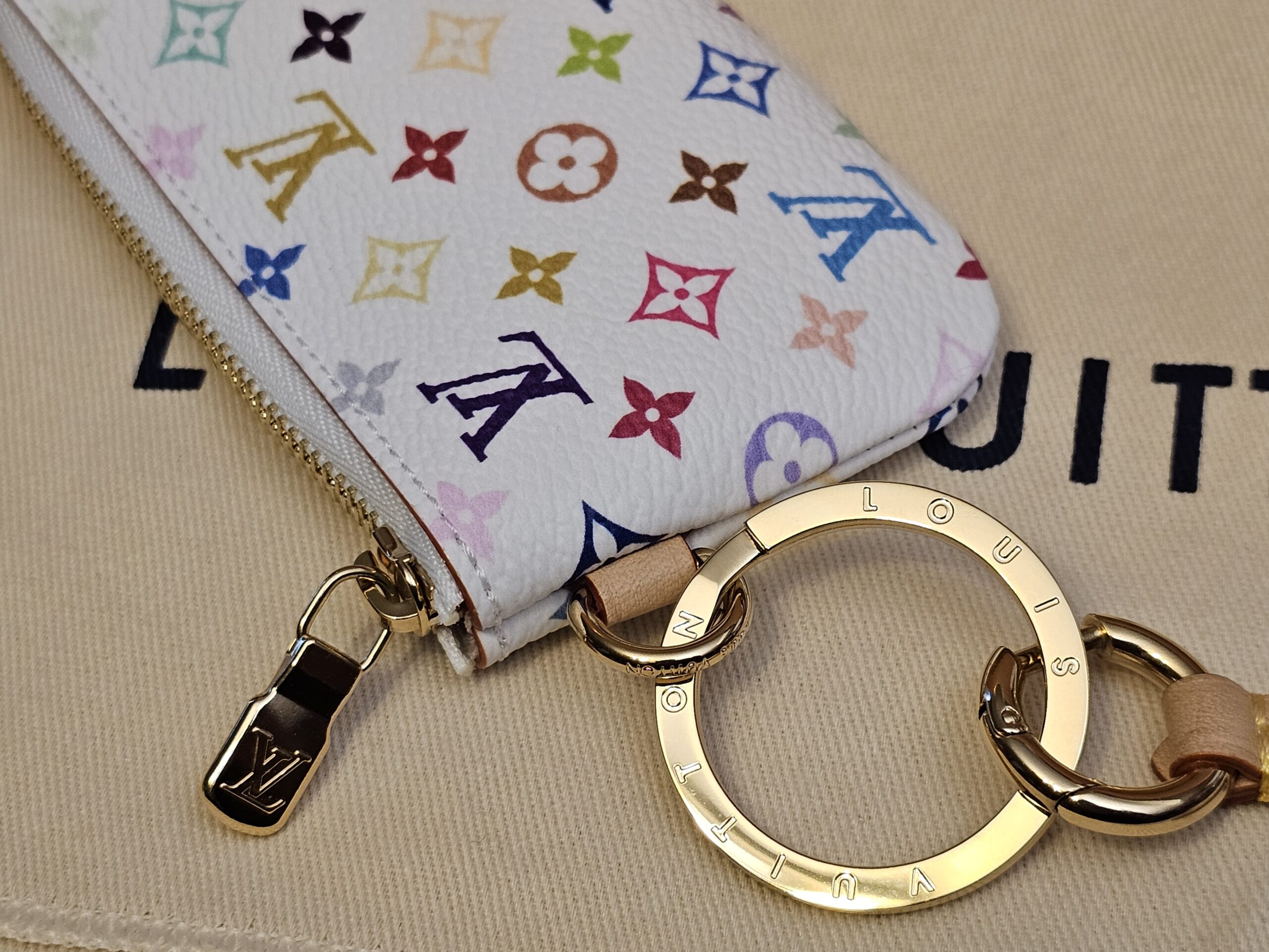 Gold-tone key ring and LV zip pull at the side
