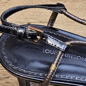 Black patent strap with gold-tone buckle over the footbed