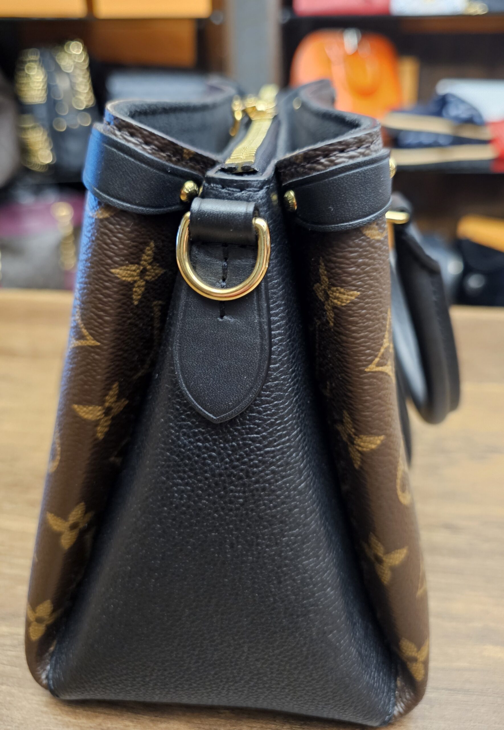 Side view showing the black grained leather side panel and strap ring