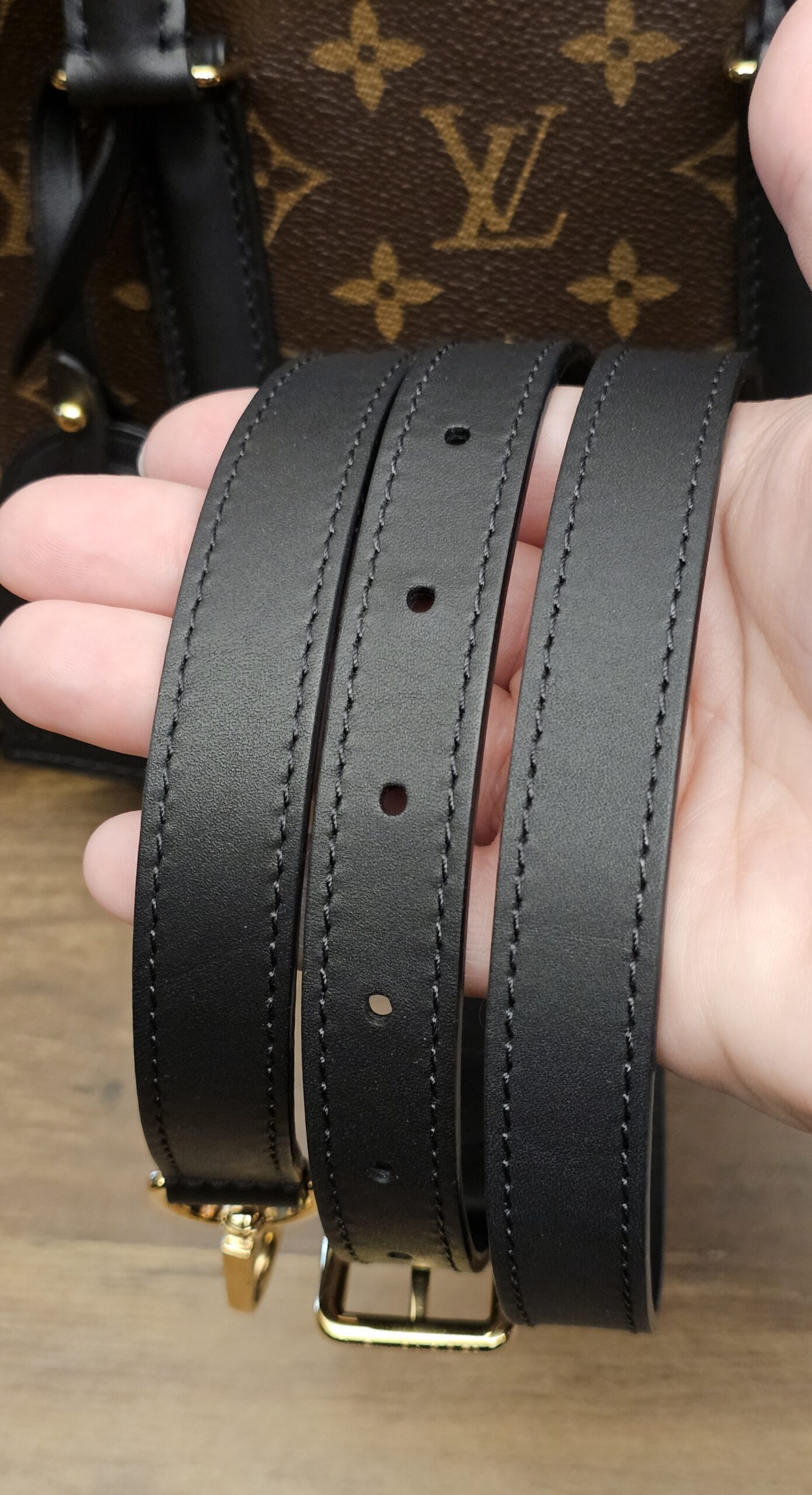 Removable black leather shoulder strap held in hand