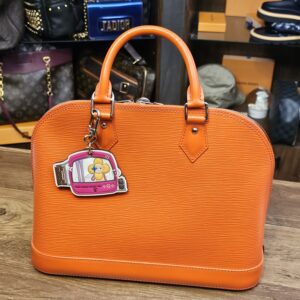 Charm clipped to an orange handbag for scale