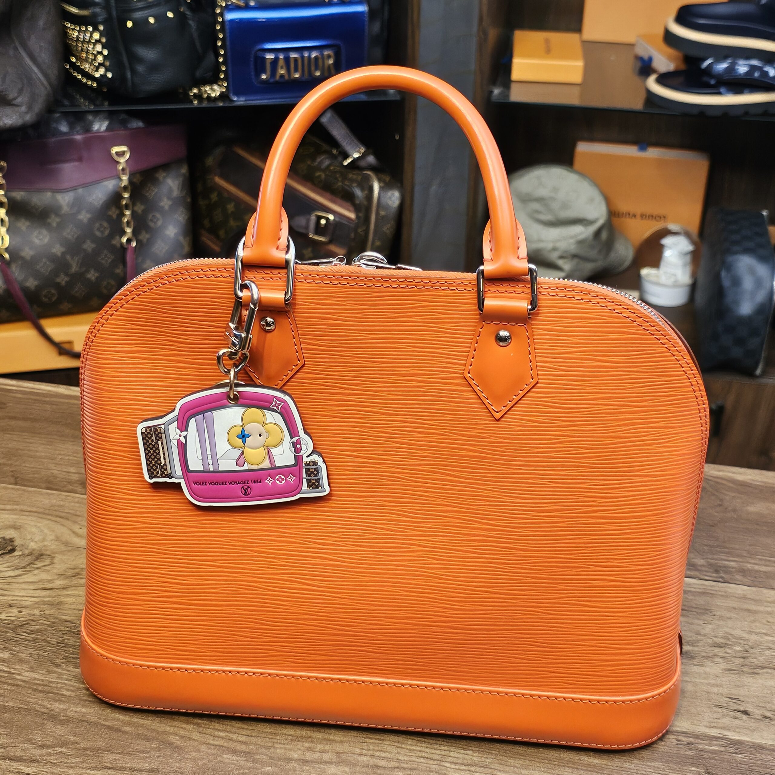 Charm clipped to an orange handbag for scale