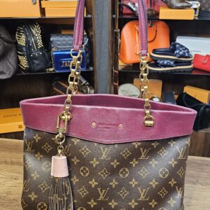 Tassel charm hanging from a Monogram tote for scale