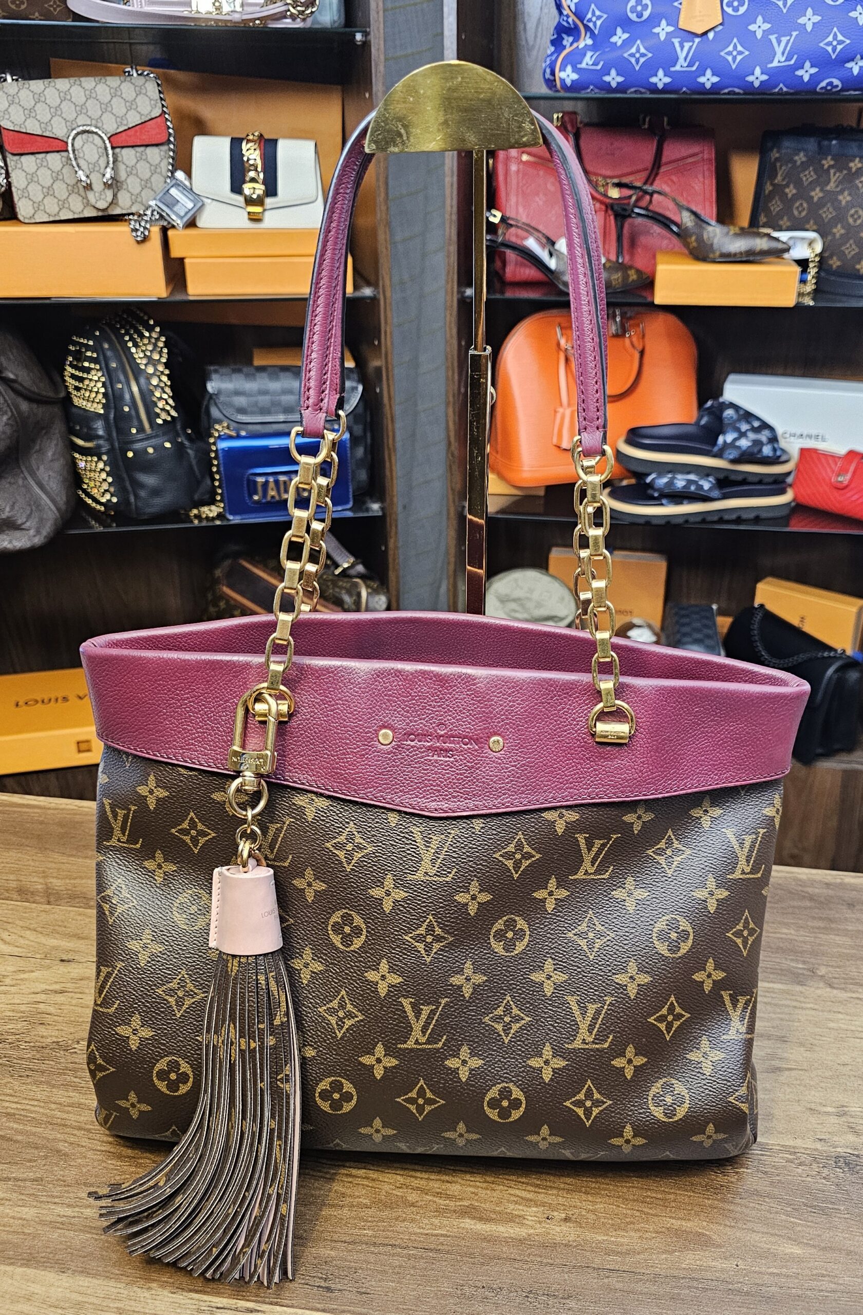 Tassel charm hanging from a Monogram tote for scale