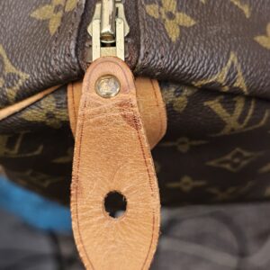 Zipper pull tab showing darkened vachetta