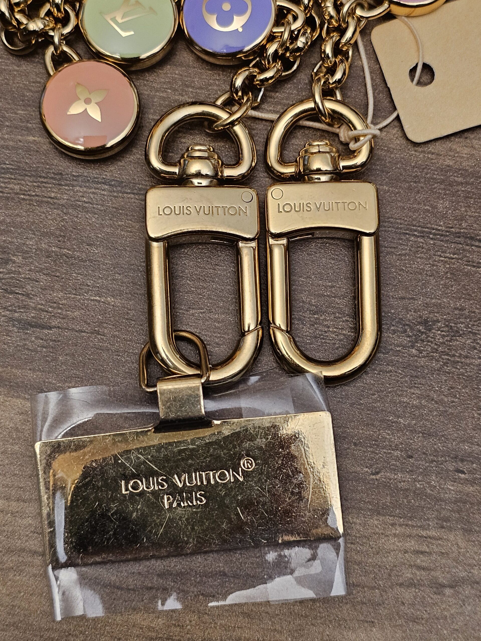 Two engraved lobster clasps and the logo plate in its protective film