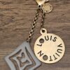 Louis Vuitton Tahitienne Key Holder and Bag Charm - gray resin charm and cutout logo disc on a gold-tone chain