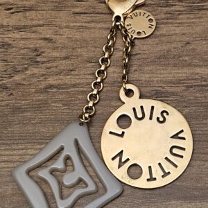 Louis Vuitton Tahitienne Key Holder and Bag Charm - gray resin charm and cutout logo disc on a gold-tone chain