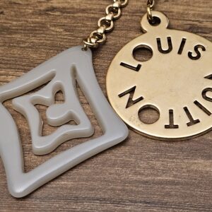 Close up of the gray resin charm and the cutout logo disc
