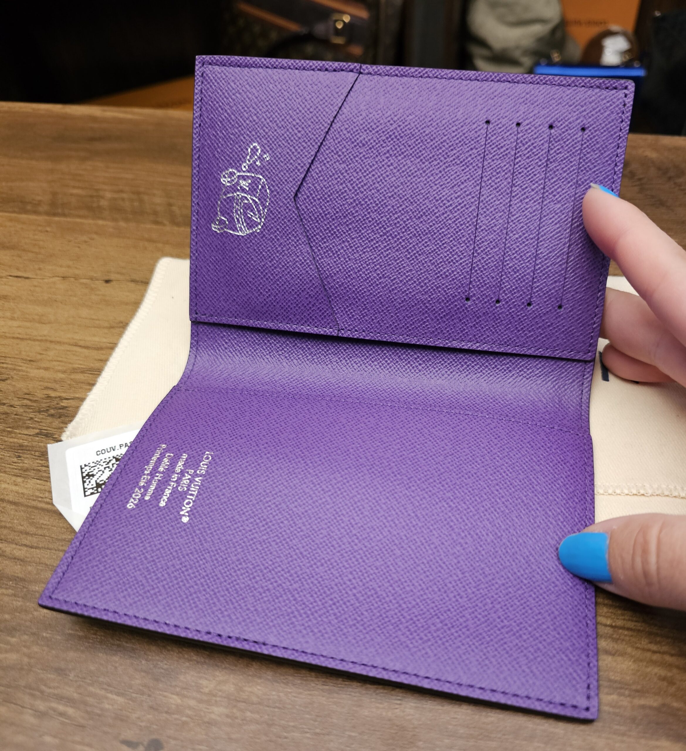 Open cover showing the purple leather interior, card slots and travel illustration