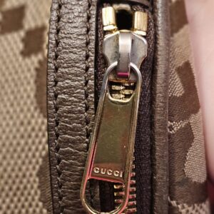 Gold-tone zip pull engraved with the logo
