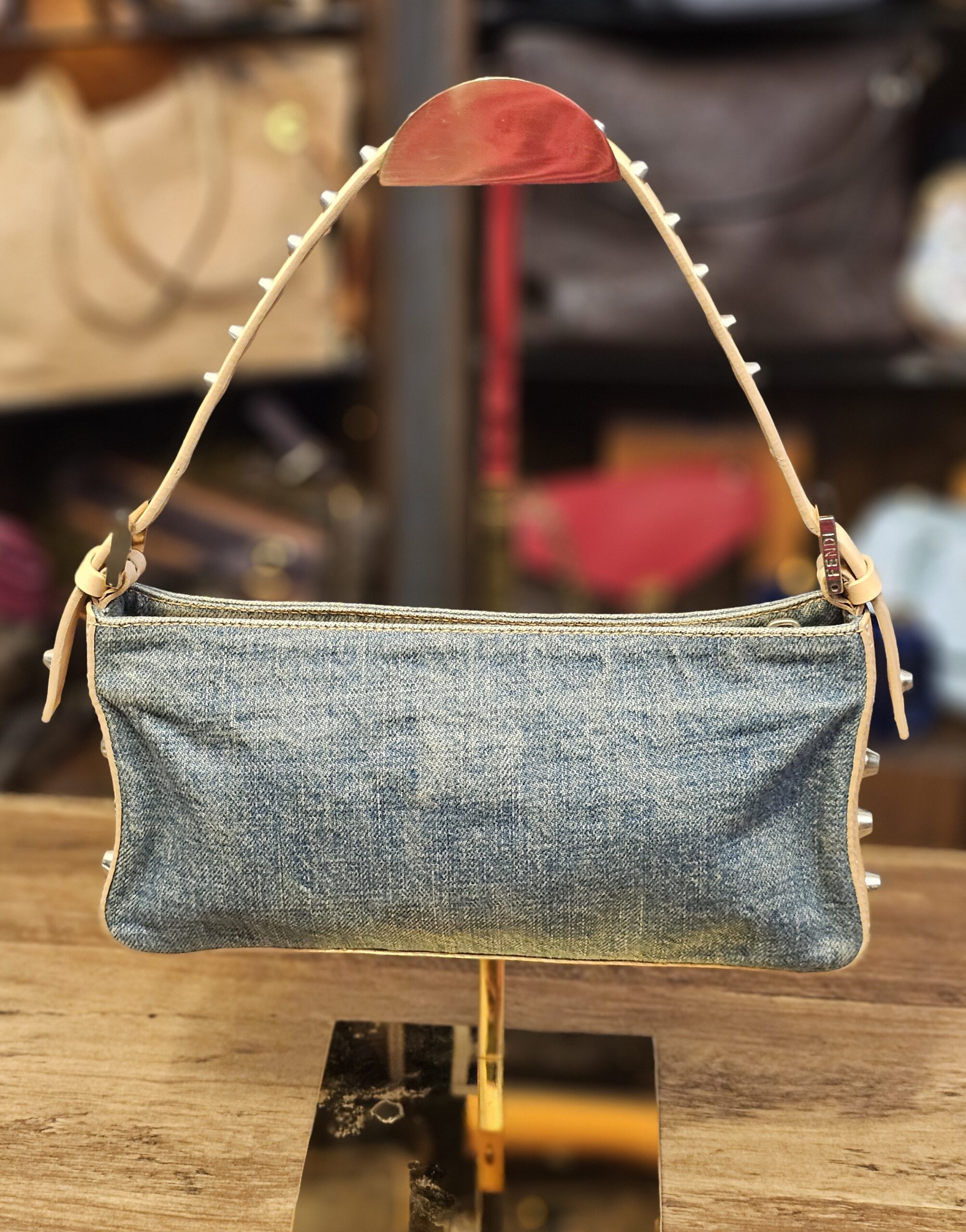 The bag, front view on a stand with the studded shoulder strap